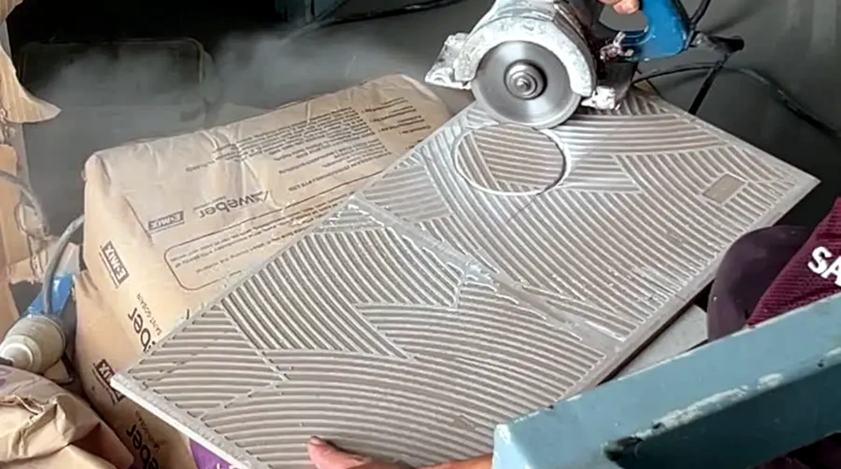 Tiling contractor in Singapore cutting a large-format tile, combed adhesive ridges visible across the back