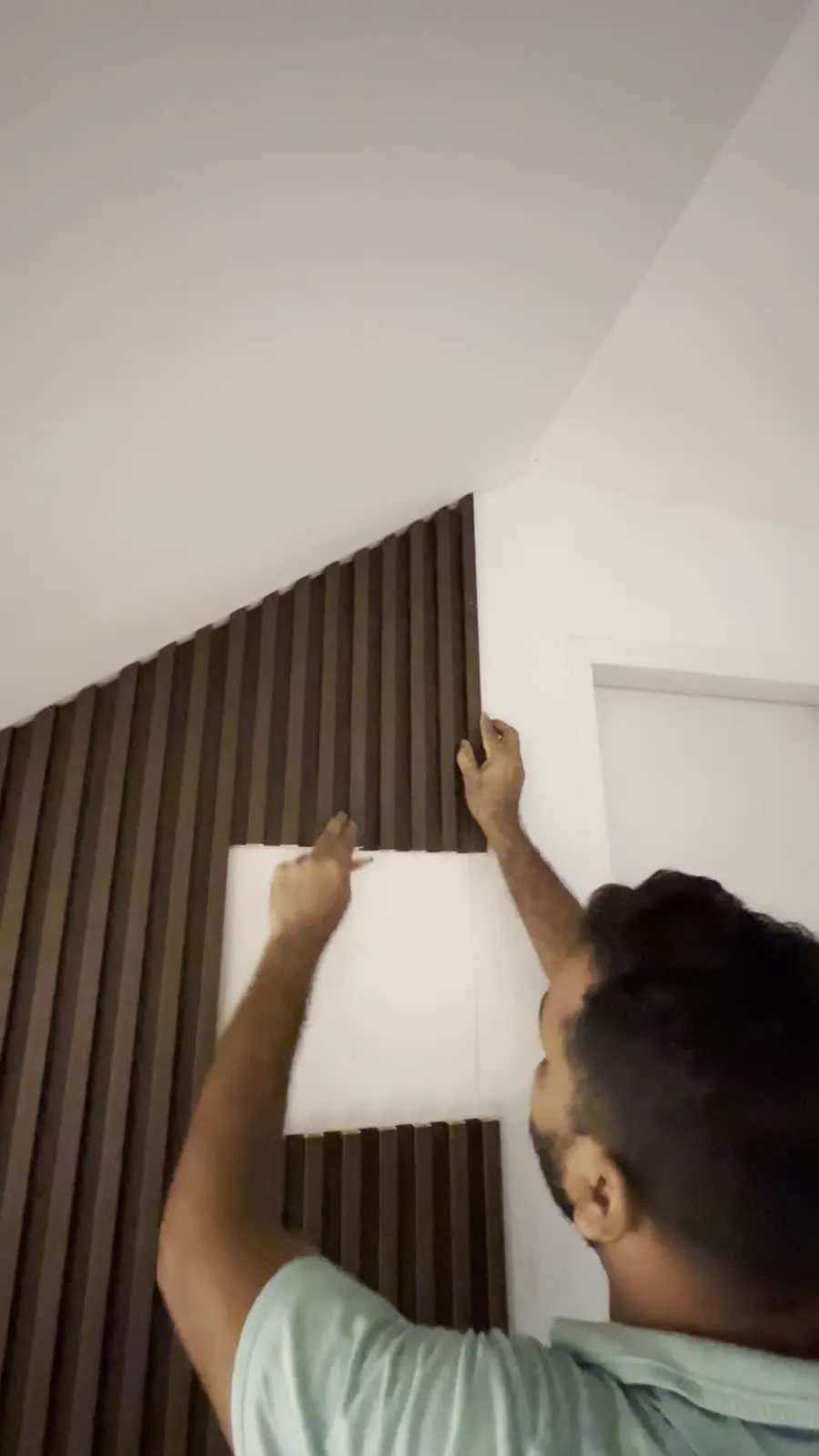 LN Flooring installer fitting dark fluted wall panels around a doorway at 44A Circular Road, Singapore