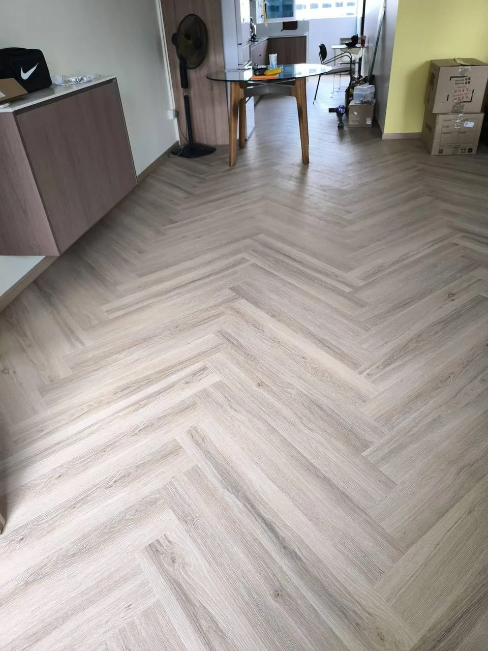 Pale oak herringbone LVT vinyl laid through a Singapore flat dining and kitchen area
