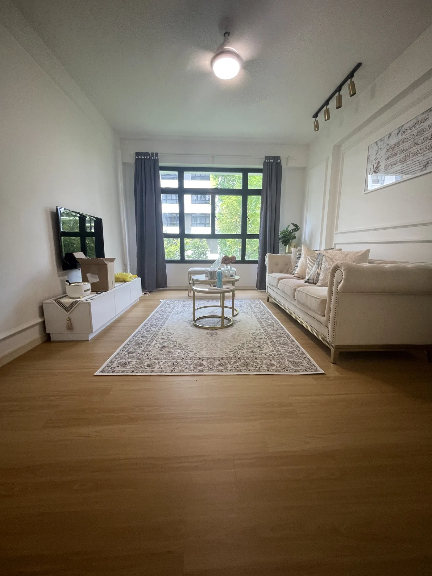 Warm oak-tone LVT vinyl flooring in a furnished HDB living room in Tampines