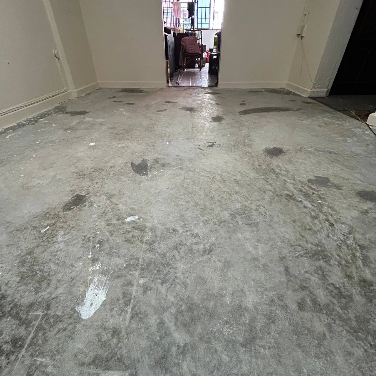 Bare cement screed floor in an HDB flat after the old finish was removed, before vinyl was laid
