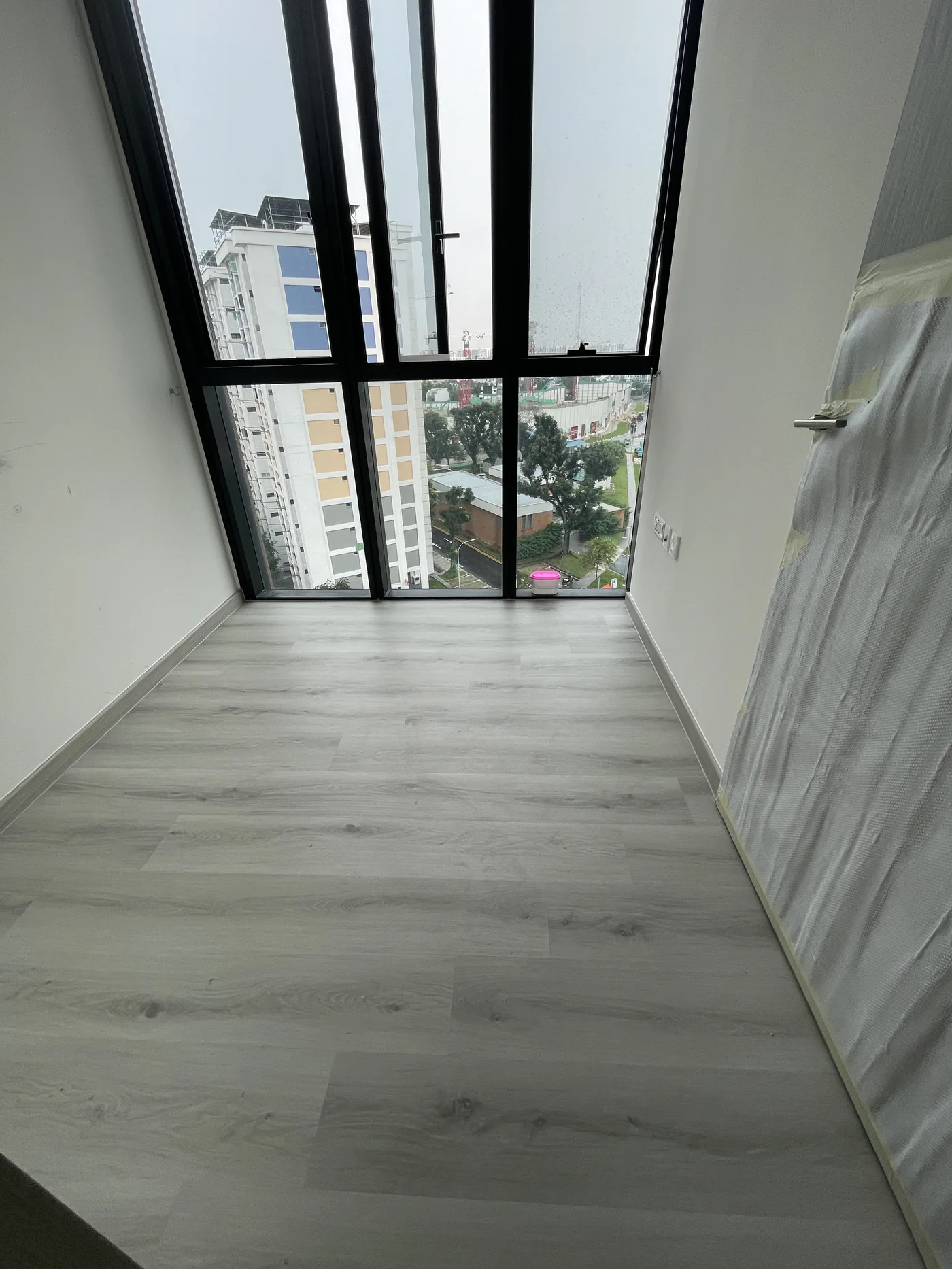 Light grey wood-look LVT vinyl planks laid in a Singapore condominium bedroom