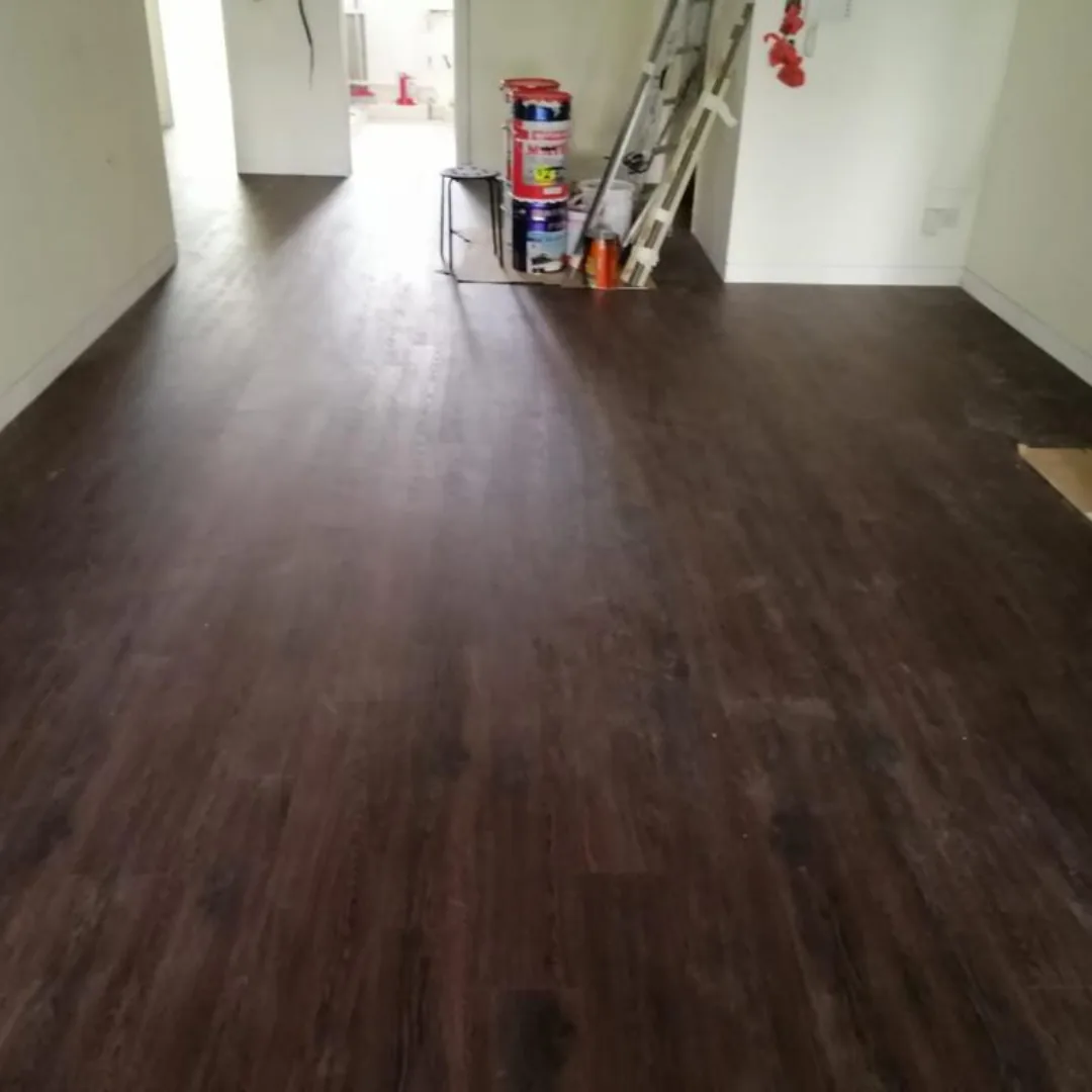 Dark walnut vinyl planks across an HDB living room