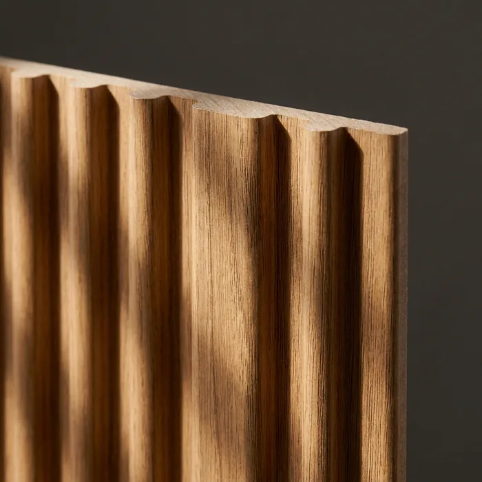 Close-up of a warm oak wood-plastic composite fluted wall panel showing the rounded rib profile
