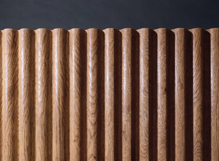 Macro close-up of a fluted wall panel: rounded oak ribs set edge to edge with no gaps