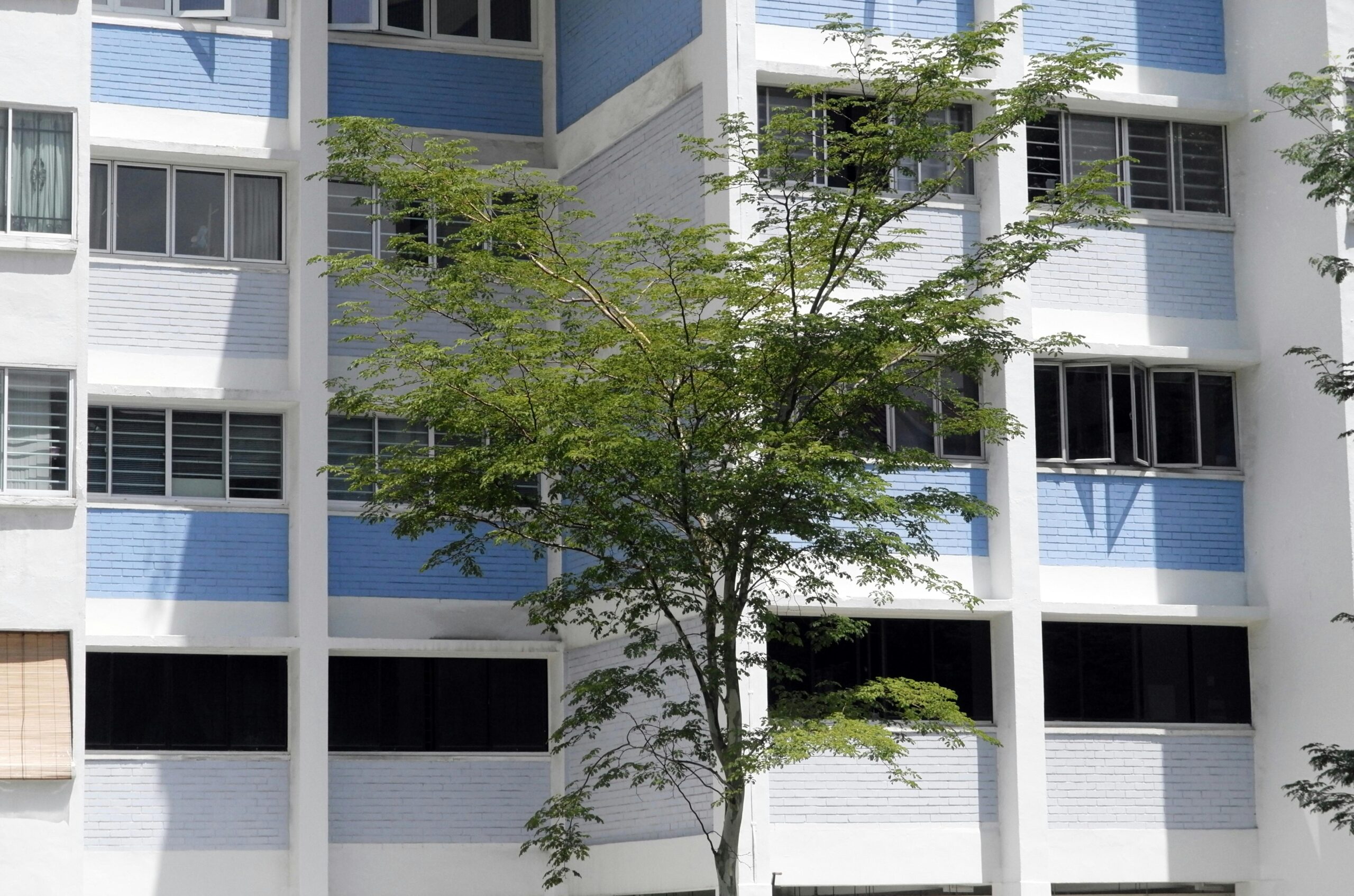 Modern residential building exterior with greenery in Singapore.