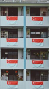 Apartment balconies decorated with Singaporean flags, celebrating National Day.