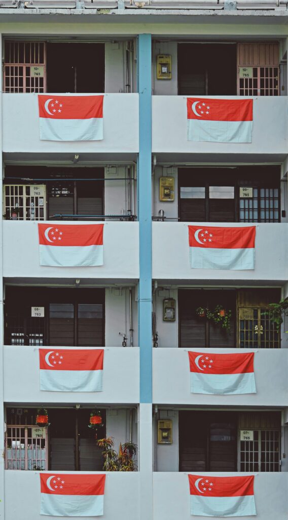 Apartment balconies decorated with Singaporean flags, celebrating National Day.